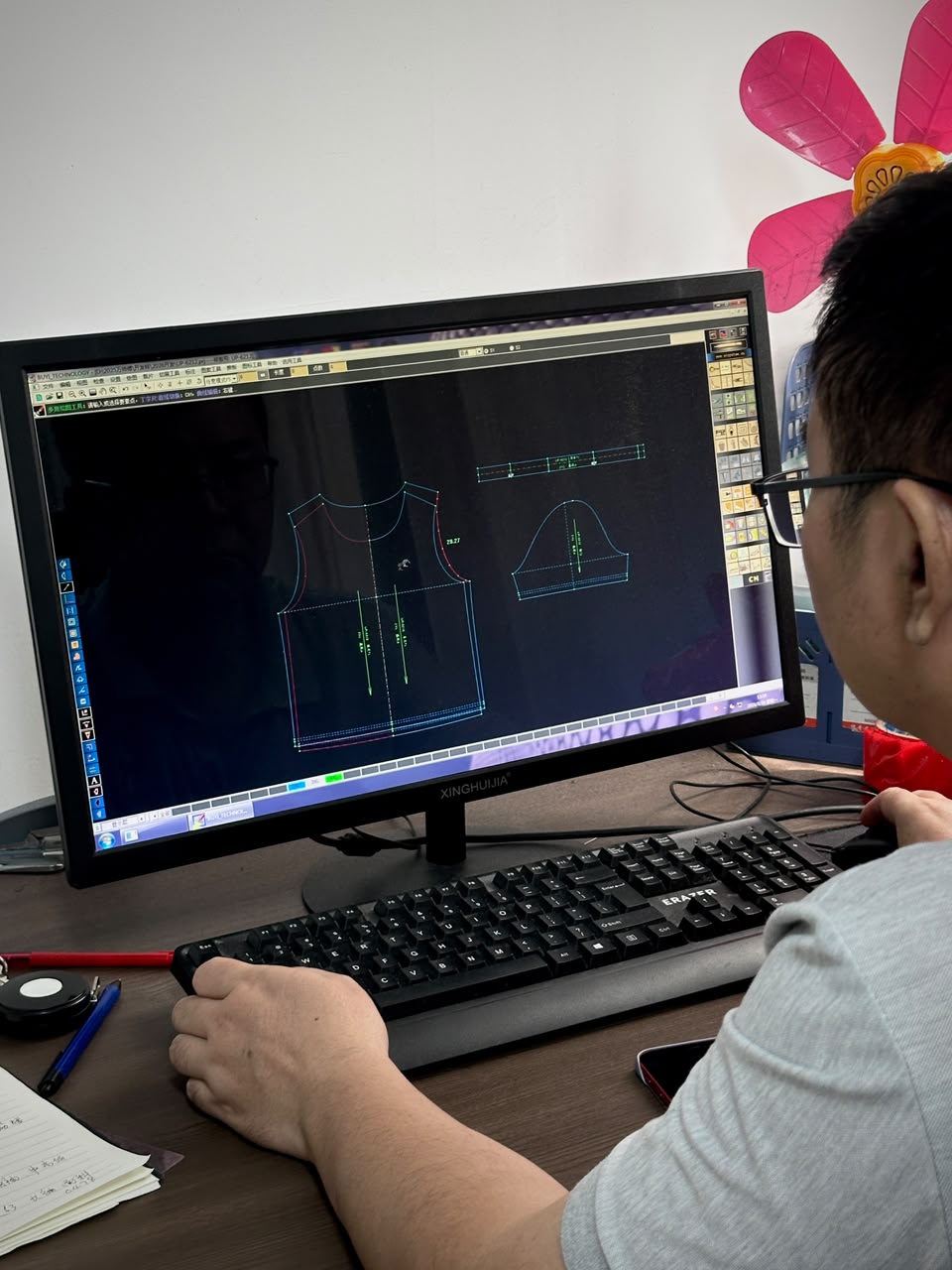 Pattern maker working on garment patterns at a computer